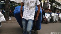 Para buruh mengangkut barang dagangan menggunakan troli di kawasan Pasar Tanah Abang, Jakarta.