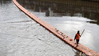 Petugas melakukan pembersihan sampah di Banjir Kanal Barat, Jakarta.