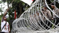 Pendukung Ahok mengibarkan bendera merah putih di depan kawat berduri.