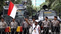 Massa pro Ahok mengibarkan bendera merah putih di depan barikade polisi.