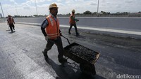 Pekerja menyiapkan material aspal.