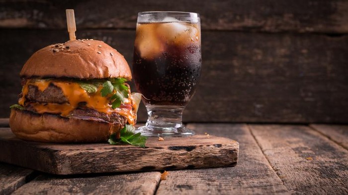fast food with burger or cheeseburger, and soft drink on vintage wooden table