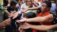 Para pengemis berebut uang receh yang dibagikan. Jumlah pengemis akan membludak pada hari Imlek.