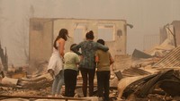 Sebuah keluarga melihat puing-puing rumah mereka yang ludes terbakar. REUTERS/Rodrigo Garrido.