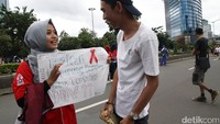 Warga yang tengah menikmati CFD melihat poster terkait HIV/Aids.