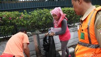 Seorang pelanggar dijatuhi sanksi memunguti sampah arena di car free day (CFD).