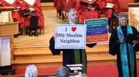 Pastur Matt Braddock dari Gereja Kristus di pinggiran kota Washington, menyuarakan dukungannya terhadap warga muslim lewat poster yang di pegangnya. REUTERS/Pool.