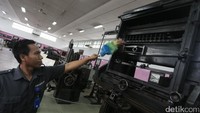 Seorang pekerja tengah melakukan perawatan terhadap mesin pencetak uang yang diproduksi sejak abad ke-20.