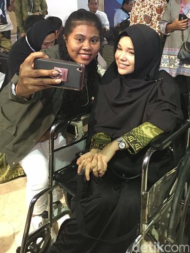 Foto: Dewi Sandra Berjilbab Syar'i dan Pakai Kursi Roda Sebelum Umrah
