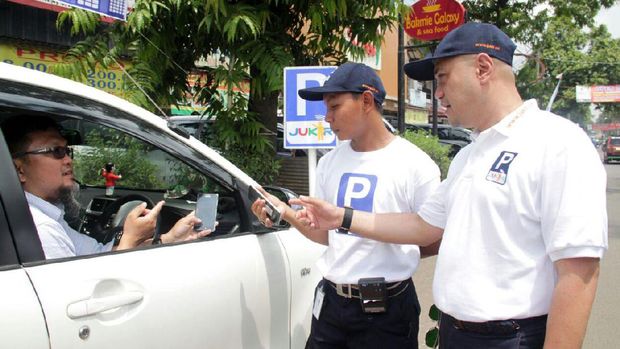 Direktur Komersial Jukir Arif Fadilah (kanan), menyaksikan seorang juru parkir melakukan transaksi melalui smartphone dengan seorang pengendara mobil.