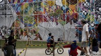 Warga yang sedang menikmati sore di ruang terbuka hijau Kalijodo itu melihat seniman membuat grafiti.