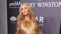 Paris Hilton tampak elegan dengan dress berwarna gold yang senada dengan rambut blondenya. Craig Barritt/Getty Images for FIJI Water