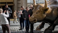 Sejumlah warga terlihat berfoto di patung banteng di distrik keuangan, New York. Setelah 48 jam, salju mulai turun hingga menutup jalan setebal 30 sentimeter. Drew Angerer/Getty Images.