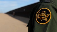 Petugas patroli perbatasan berdiri di samping Tembok Trump, di California (8/2). (Mike Blake/Reuters)