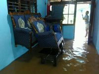 Warga mengikat kursi ruang tamu agar tak terendam banjir
