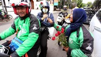 Seorang driver Go-Jek membagikan bunga kepada penumpang Go-Ride.