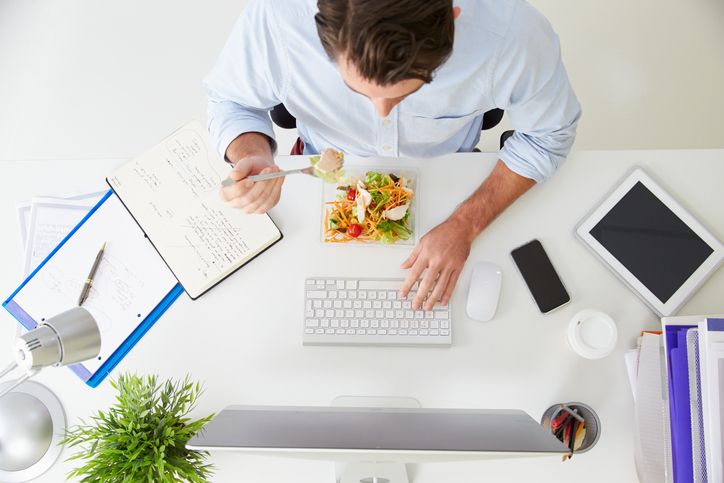 Overhead View Of Businessman Working At Computer In Office Eating Lunch