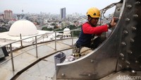 Seorang relawan membersihkan bagian puncak menara.