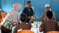 Warga menyerahkan undangan pencoblosan kepada petugas KPPS.