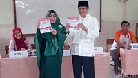 Embay menunjukkan surat suara sebelum mencoblos.