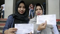 Dua orang warga menunjukkan undangan pencoblosan di Rusun Jatinegara Barat, Kampung Melayu, Jakarta, Rabu (15/2/2017).