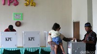 Warga memasukkan surat suara ke kotak suara.