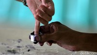 Seorang warga mencelupkan jari kelingkingnya ke tinta.