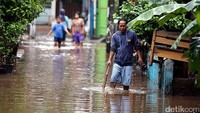 Sejumlah warga melintas di jalanan yang terendam banjir.