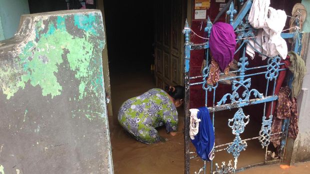 Ibu-ibu membersihkan rumah usai banjir surut.