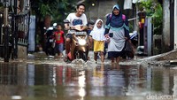 Pengendara sepeda motor menerobos banjir di Cipinang Melayu.