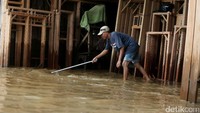 Seorang warga membersihkan lumpur yang terbawa banjir.