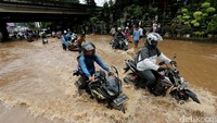 Beberapa pengendara sepeda motor nekat melintas banjir.