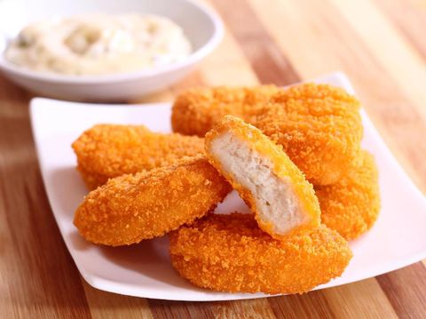A pile of chicken nuggets on white plate with sauce
