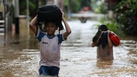 Dua orang pelajar SD tengah menerobos banjir.