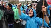 Walaupun hujan mengguyur, massa tetap berorasi.