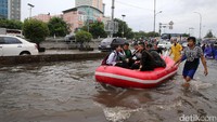 Warga dan pengguna jalan menerobos banjir dengan perahu karet.