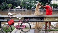Debit air yang meningkat membuat sejumlah warga memanfaatkan momen tersebut untuk mencari ikan.
