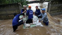 Pasukan Biru berjibaku menutup tanggul yang jebol di belakang Perumahan Cipinang Indah, Jakarta Timur, Selasa (21/2/2017).