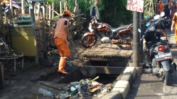 Petugas PPSU membersihkan sampah dan lumpur sisa banjir.