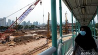 Seorang pejalan kaki terlihat melintas di JPO yang bersebelahan dengan proyek Pasar Rumput.