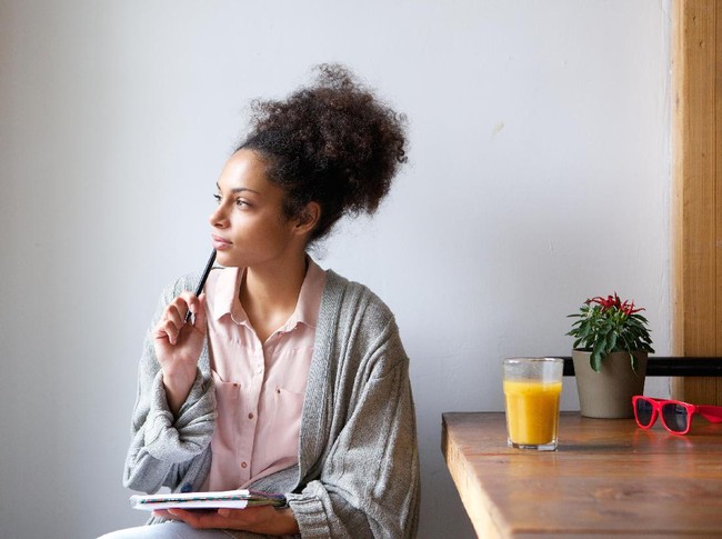 Portrait of a young woman sitting at home with pen and paper