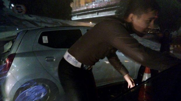 Polisi menangani mobil LCGC yang tertimpa papan reklame di dekat Menara Peninsula Slipi