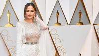 Chrissy Teigen terlihat seksi dengan gaun putih semi-transparan dibagian depan dan belahan tinggi di bagian kaki. Frazer Harrison/Getty Images/detikFoto.