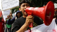 Perwakilan massa berorasi menggunakan pengeras suara.