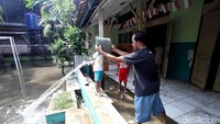 Petugas menguras air yang menggenangi ruang kelas.