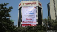 Sejumlah petugas memasang spanduk Awasi, Tegur, Laporkan. Sampaikan keluhanmu mengenai layanan publik. Cegah Maladministrasi di gedung Ombudsman Republik Indonesia (ORI).