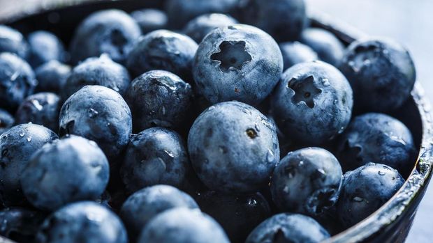 Fresh ripe garden blueberries in a white heart shape bowl on dark rustic wooden table. with copy space for your text