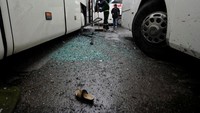 Petugas membersihkan pecahan kaca di sekitar bus. Pool/Omar Sanadiki/Reuters/detikFoto.