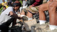 Seorang pendemo menuangkan adukan semen ke wadah tempat kaki yang akan disemen.