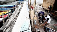 Dua orang warga mendirikan kembali rumah bedeng di atas puing-puing bangunan.